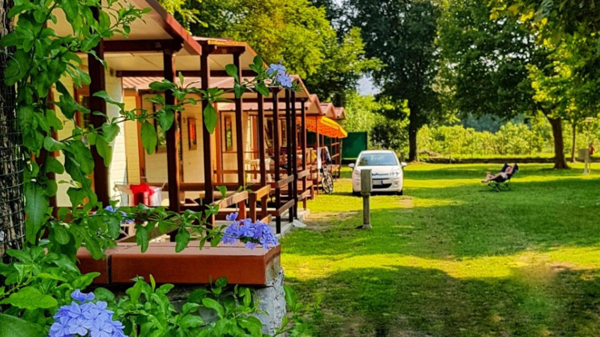 Bungalow immersi nel verde con fiori e auto parcheggiata.