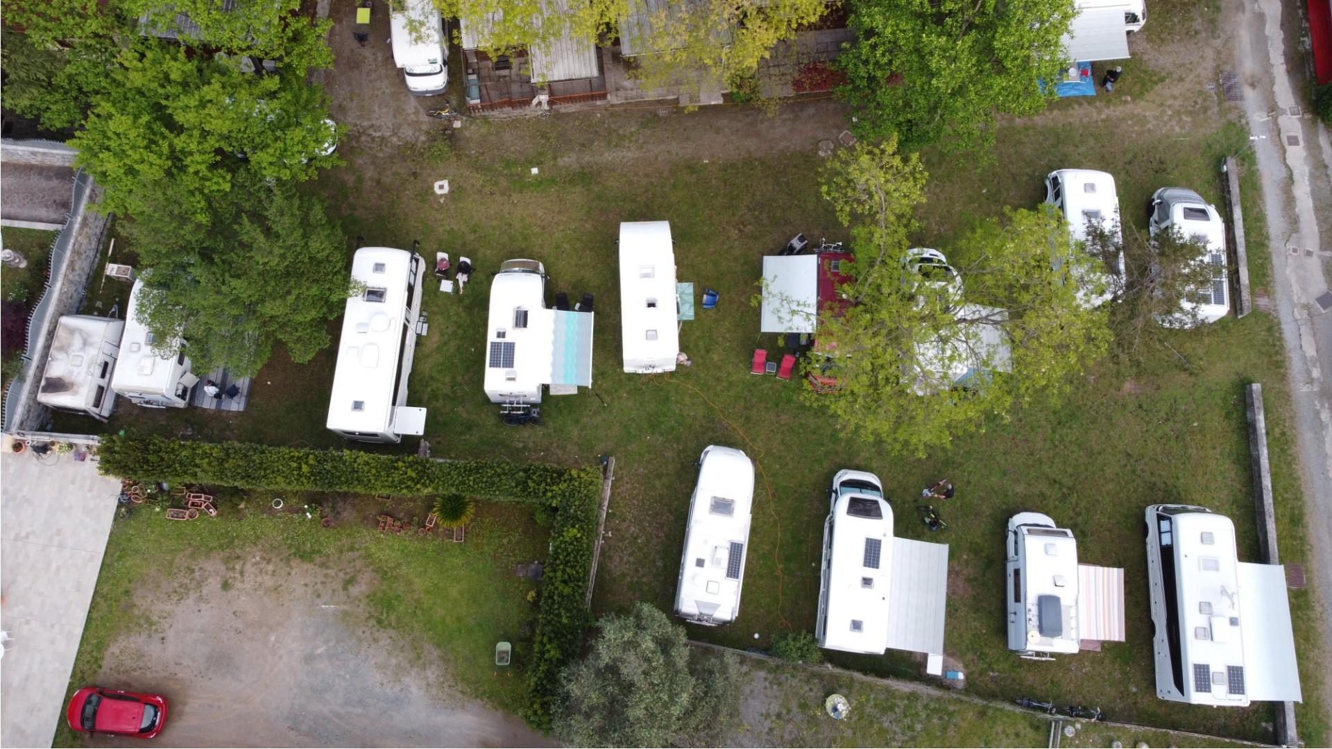 Vista aerea di un campeggio con camper e roulotte parcheggiati.