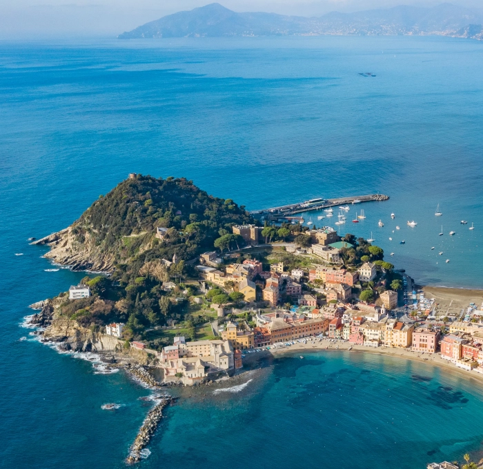 Vista aerea di una pittoresca cittadina costiera con case colorate e mare azzurro.