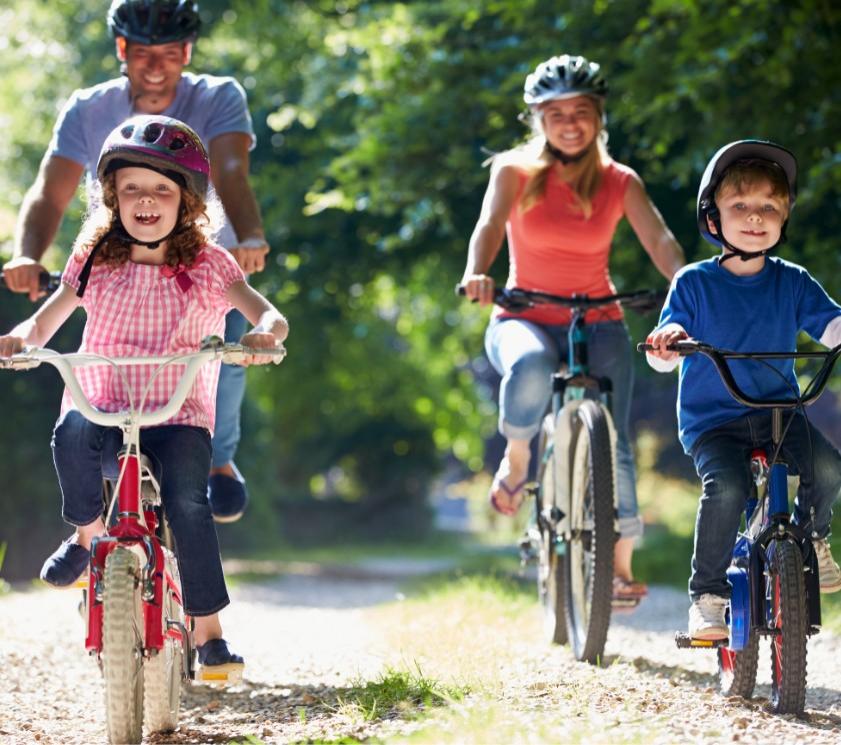 Famiglia in bicicletta su un sentiero boschivo.
