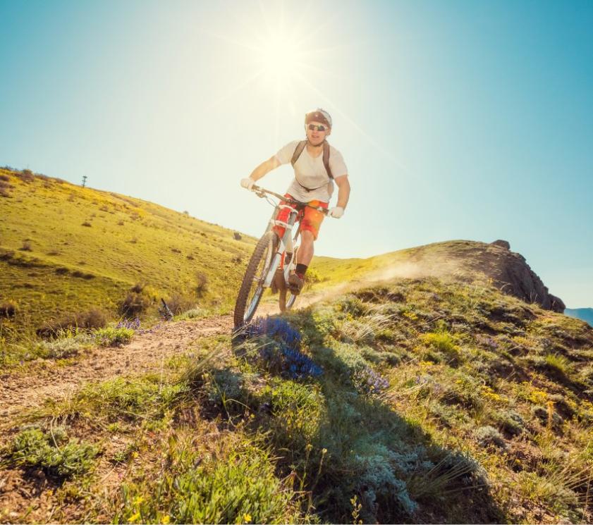 Ciclista su un sentiero di montagna sotto il sole splendente.